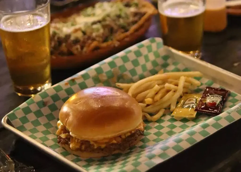 Papel cuadriculado para hamburguesas y comida rápida — Papelver - PAPELVER - PAPELVER Hamburguesa con papas servida sobre papel cuadriculado grado alimenticio Papelver